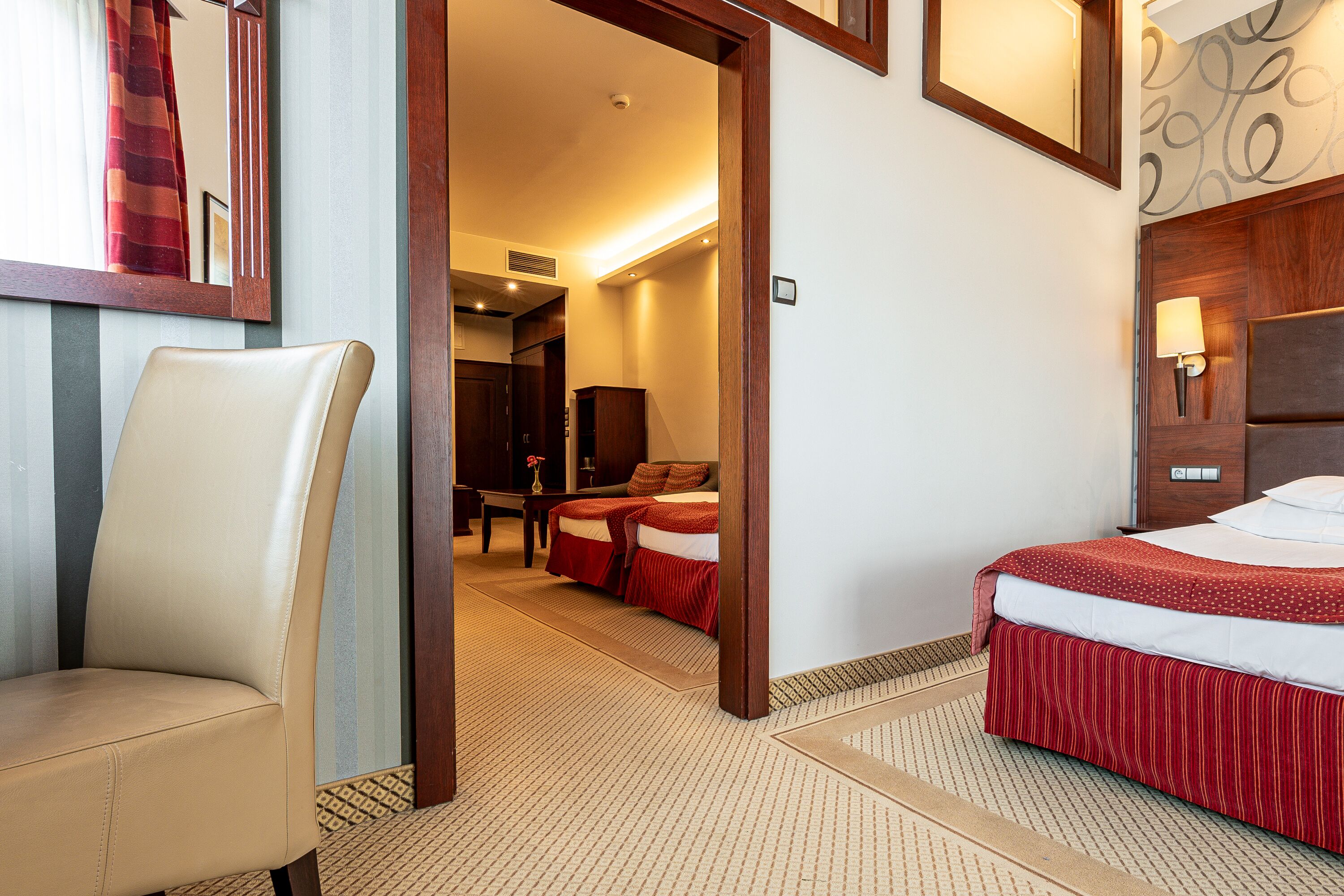 A hotel room with a bed, a chair, a desk, and a mirror.