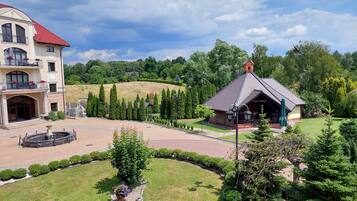 A hotel with a red roof, a fountain, and a well-maintained garden.