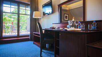 A hotel room with a desk, chair, and a large window with a view of the outdoors.