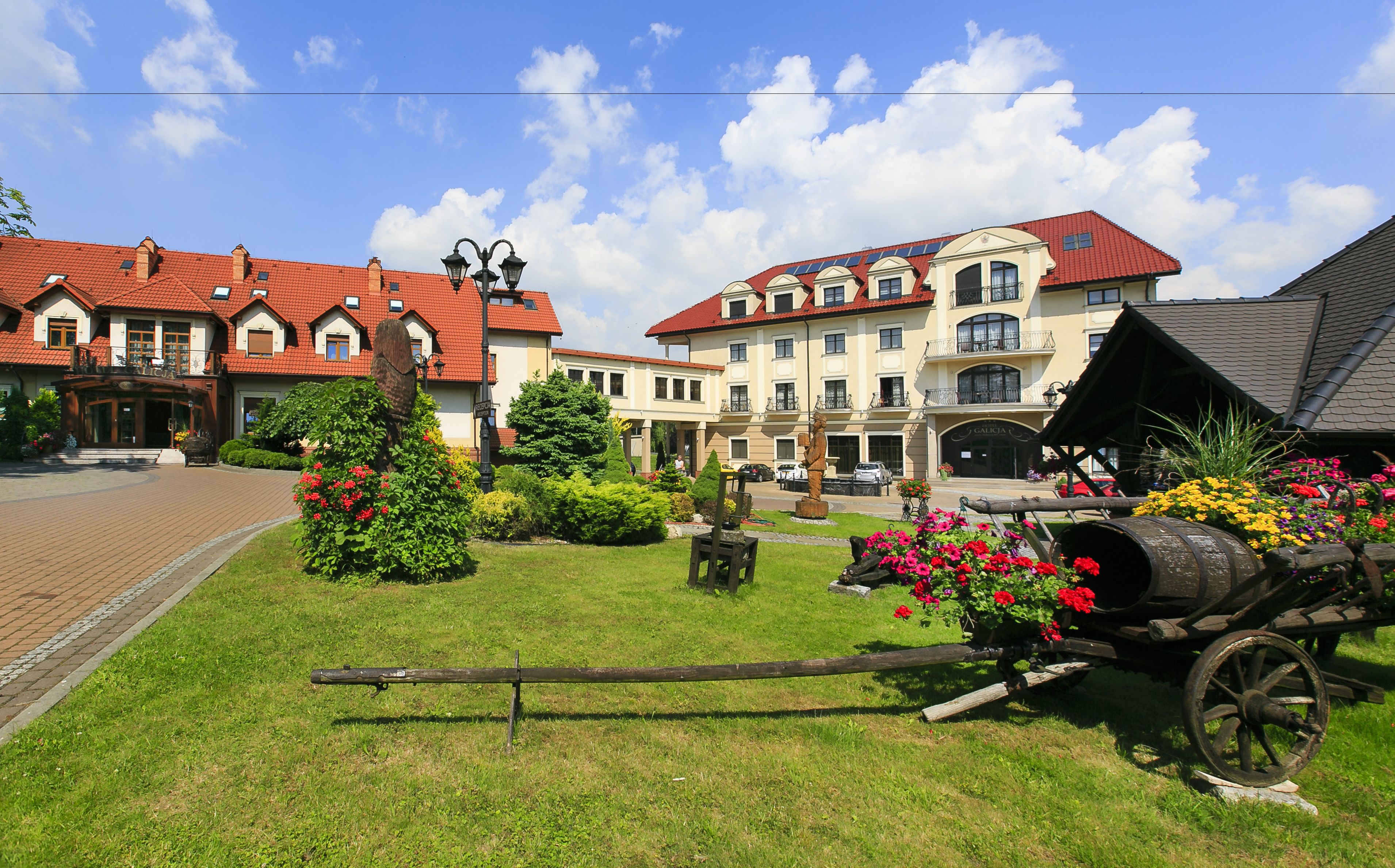 A traditional European town square with historic buildings, a statue, and a vintage cart.