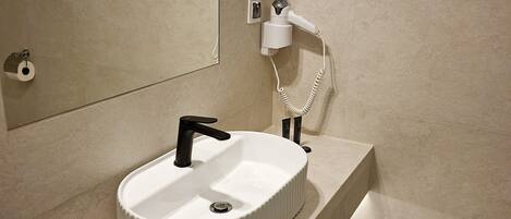 Un baño con un lavabo redondo, un espejo, un perchero y un inodoro.