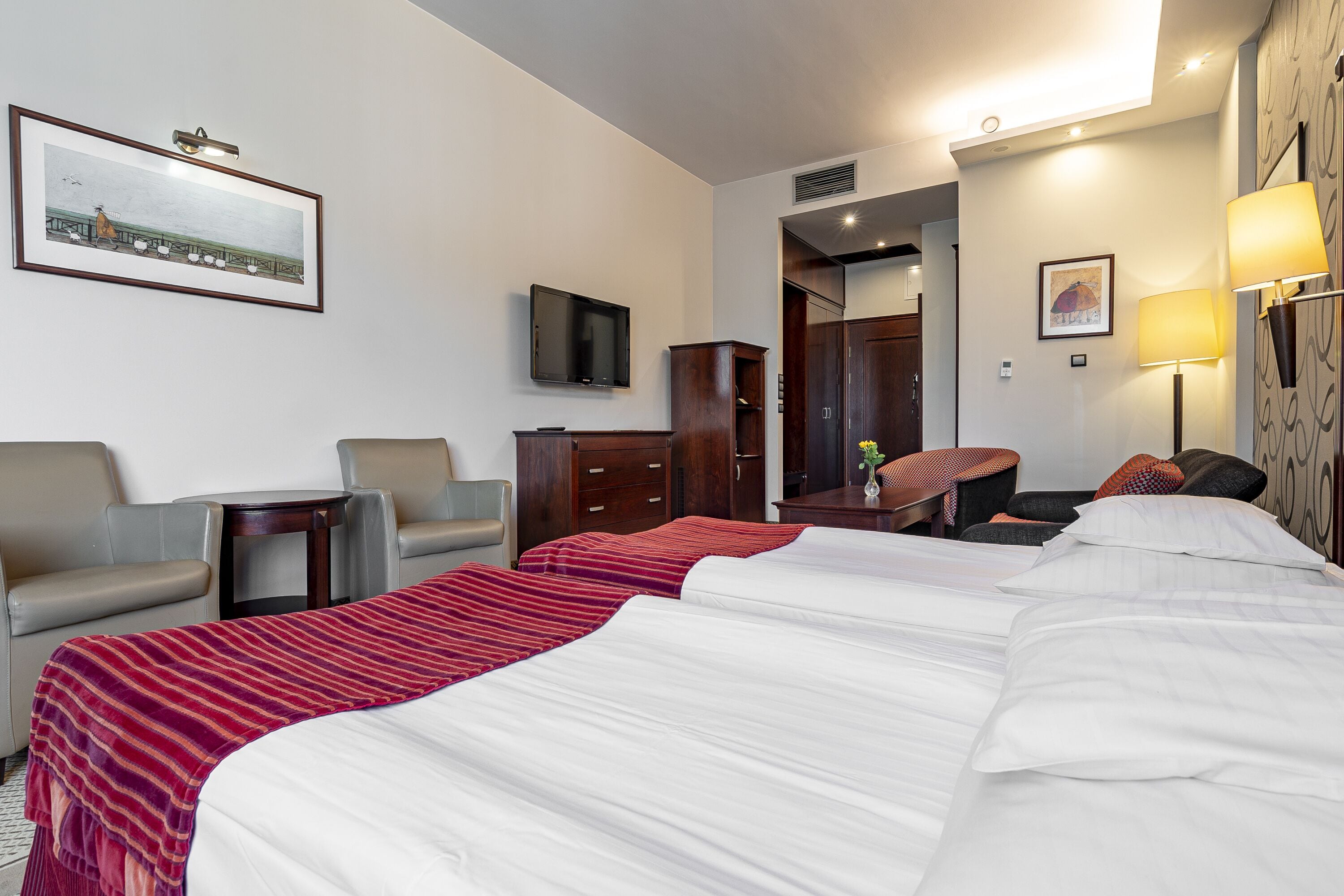 Une chambre d’hôtel avec deux lits, une télévision, un bureau et une chaise.