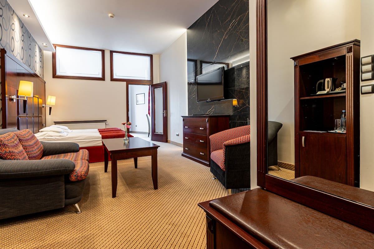 Een hotelkamer met een bed, een bank, een bureau, een televisie en een kledingkast.