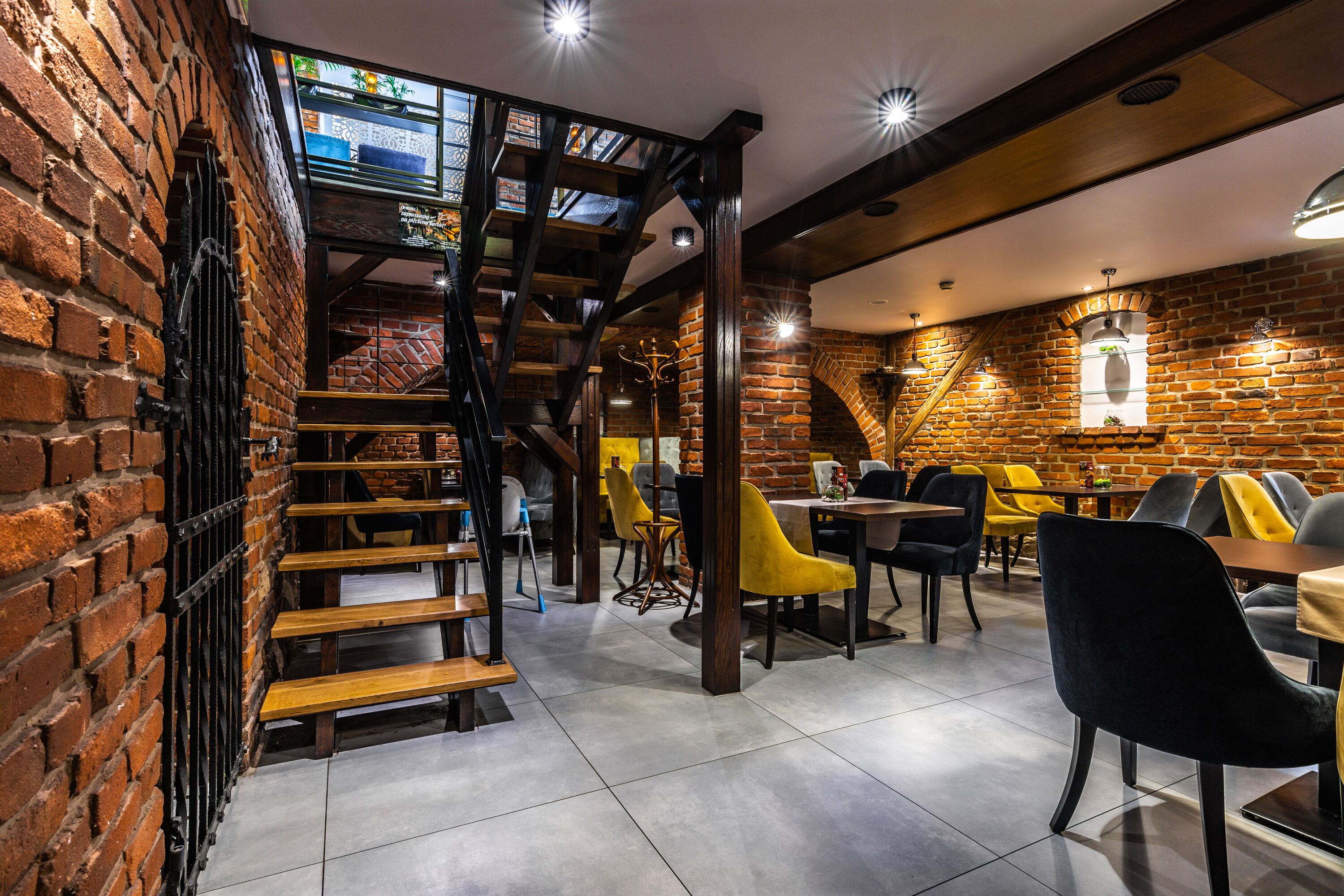 A restaurant with brick walls, wooden staircase, and modern seating.