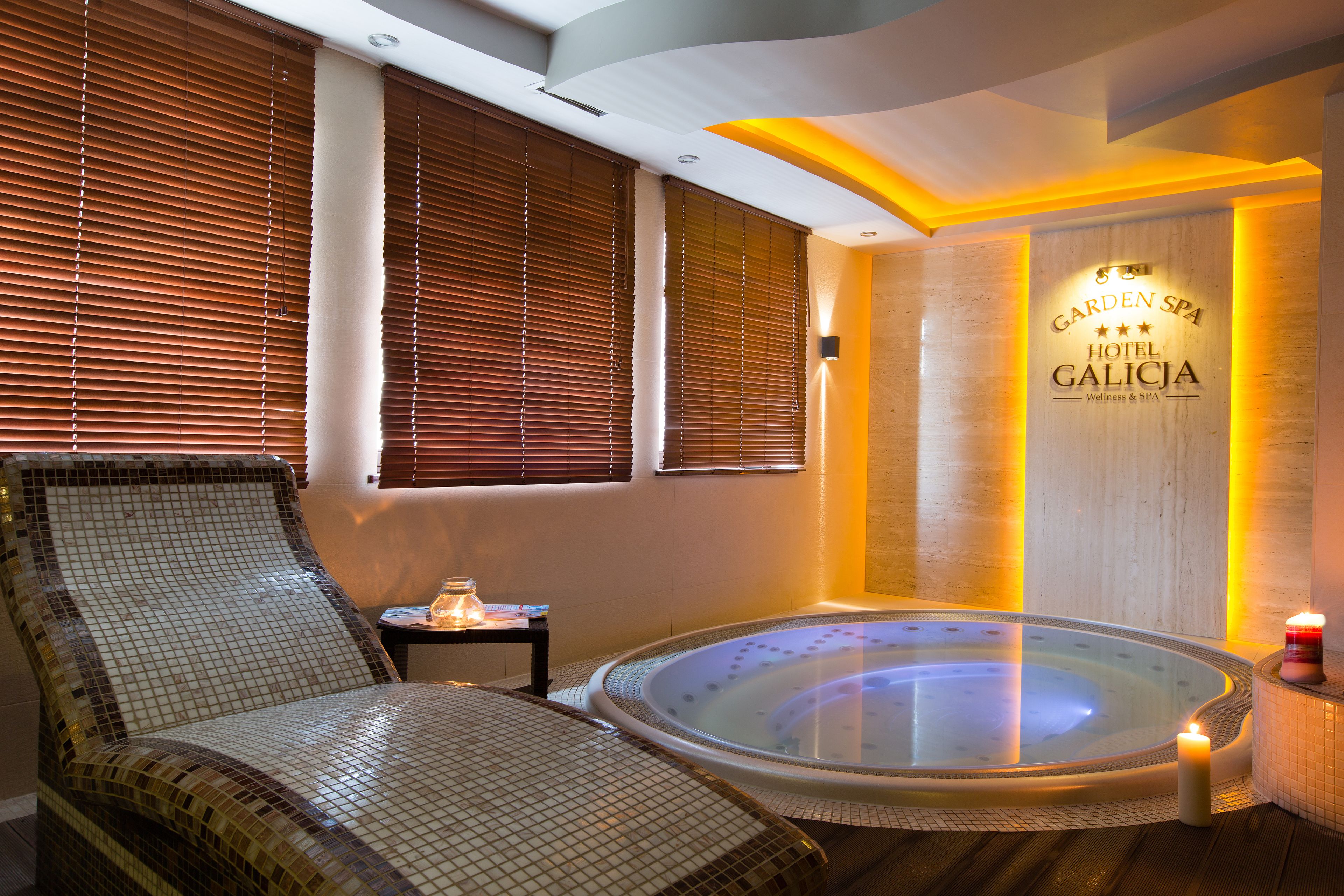 Un cuarto de spa con una bañera de hidromasaje, una silla de descanso y una pared con el nombre del hotel.