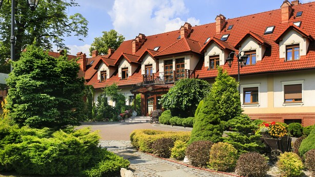A row of traditional houses with red-tiled roofs, a central courtyard, and well-maintained gardens.