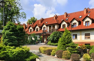 Uma fileira de casas tradicionais com telhados de telha vermelha, um pátio central e jardins bem cuidados.