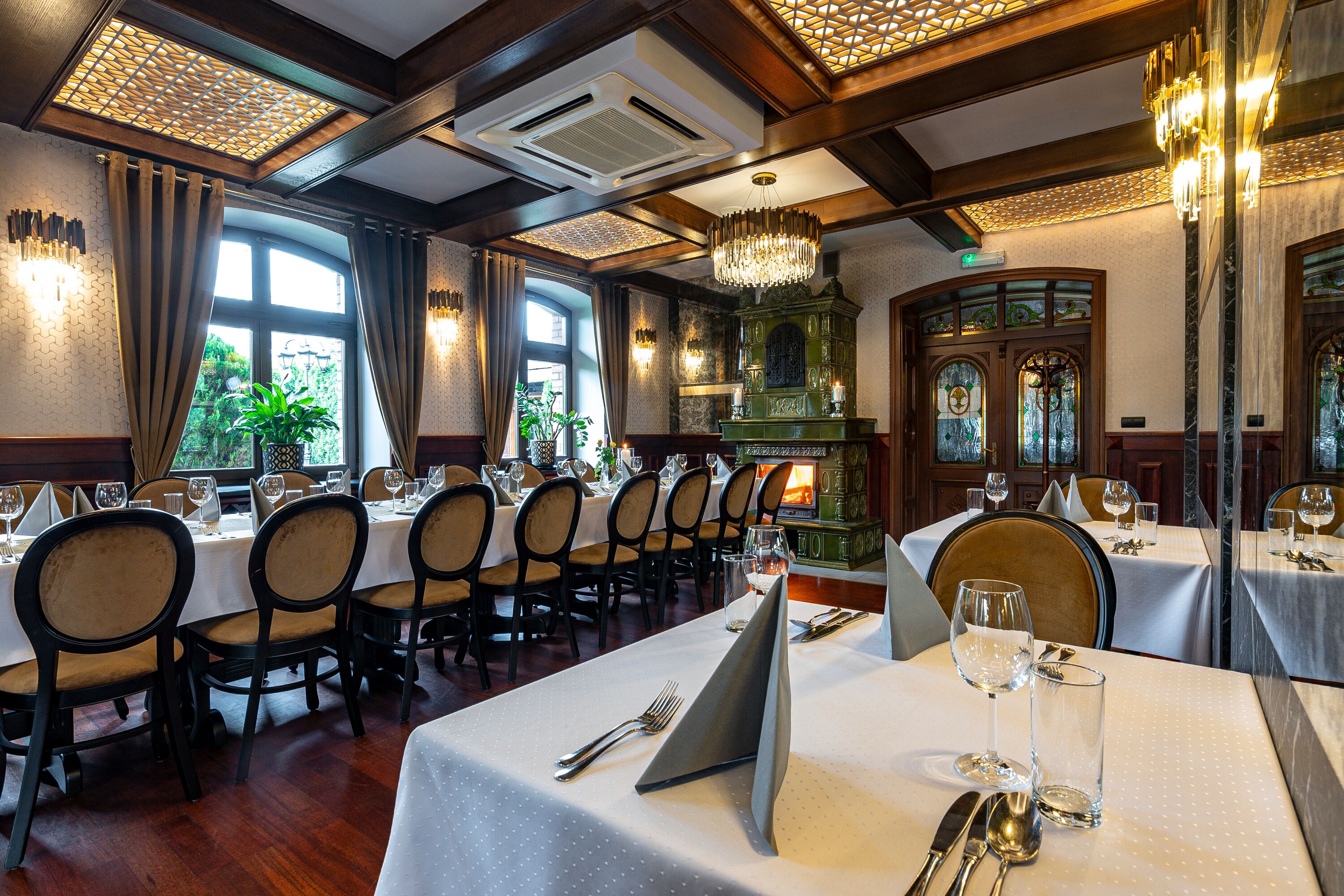 A restaurant with multiple dining tables, chairs, and a chandelier.