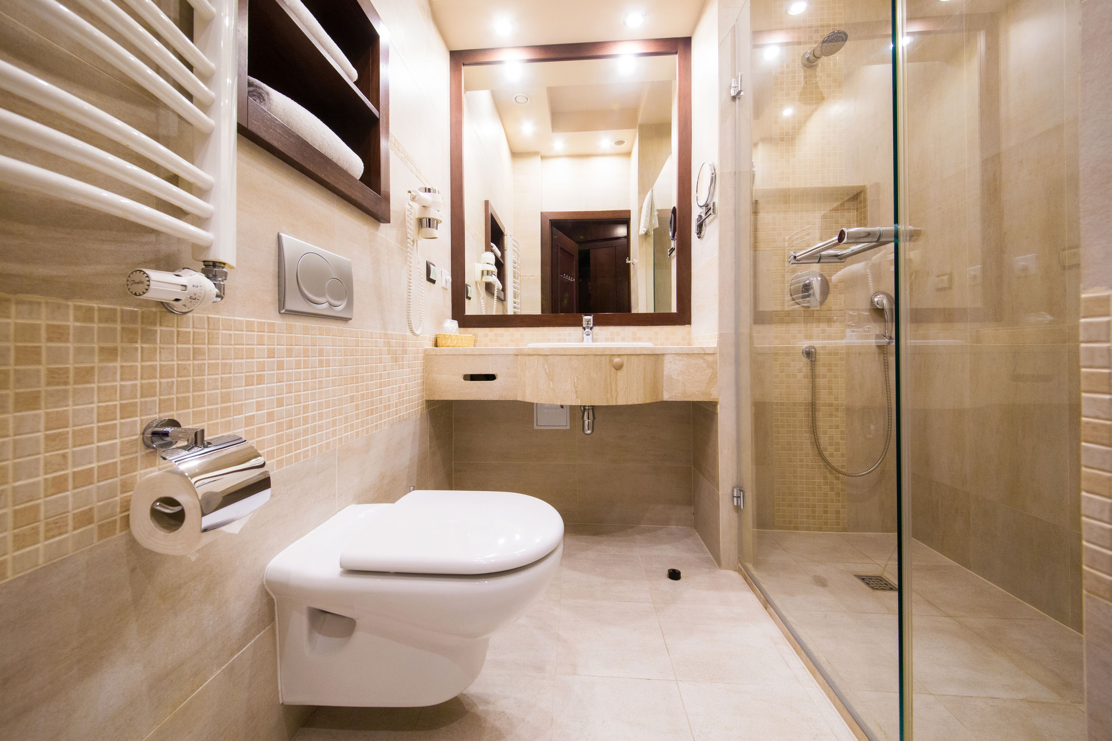 Une salle de bain moderne avec une douche à parois de verre, des toilettes et un lavabo surmonté d’un miroir.