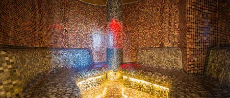 A mosaic-tiled room with a central circular design and seating areas on either side.