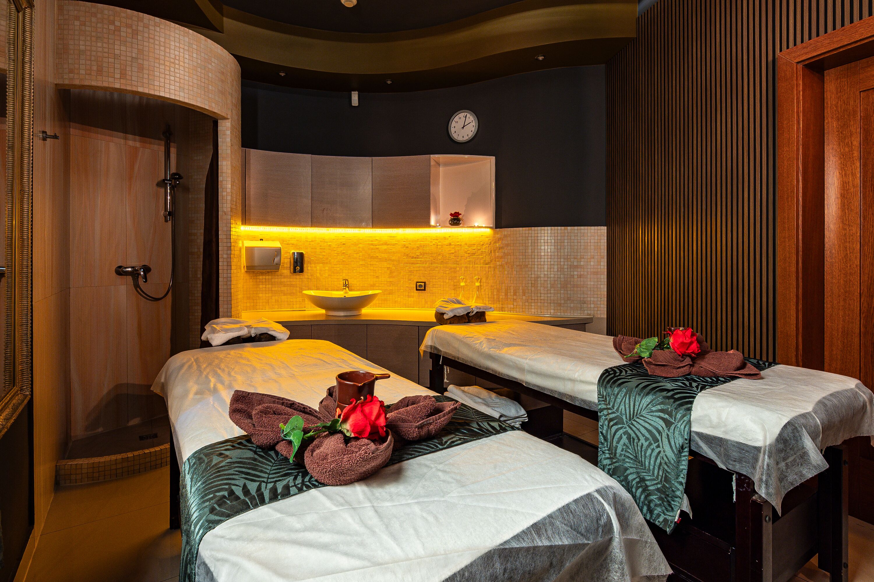 A spa room with two beds, a sink, and a shower.