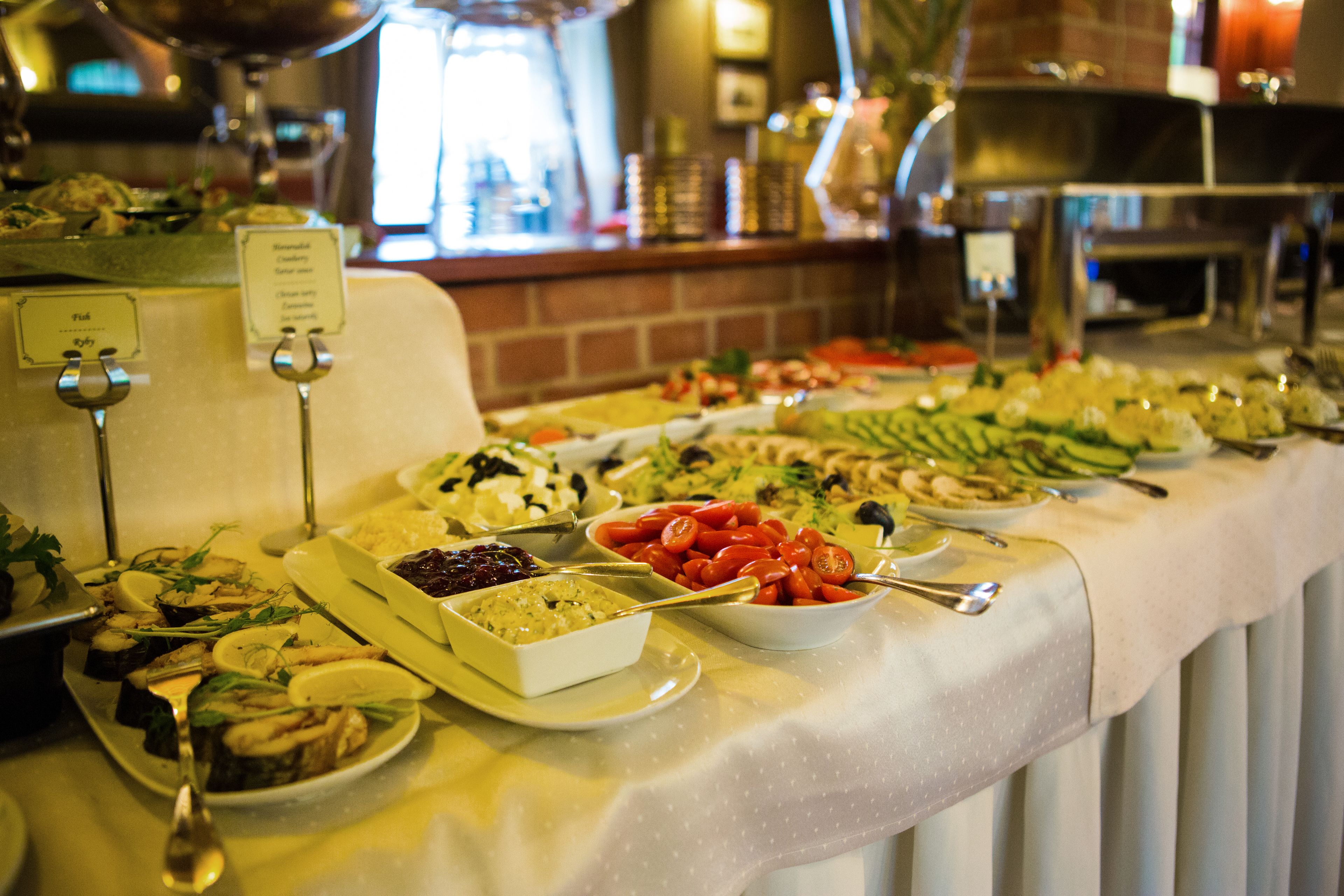 A buffet table with various food items and serving utensils.