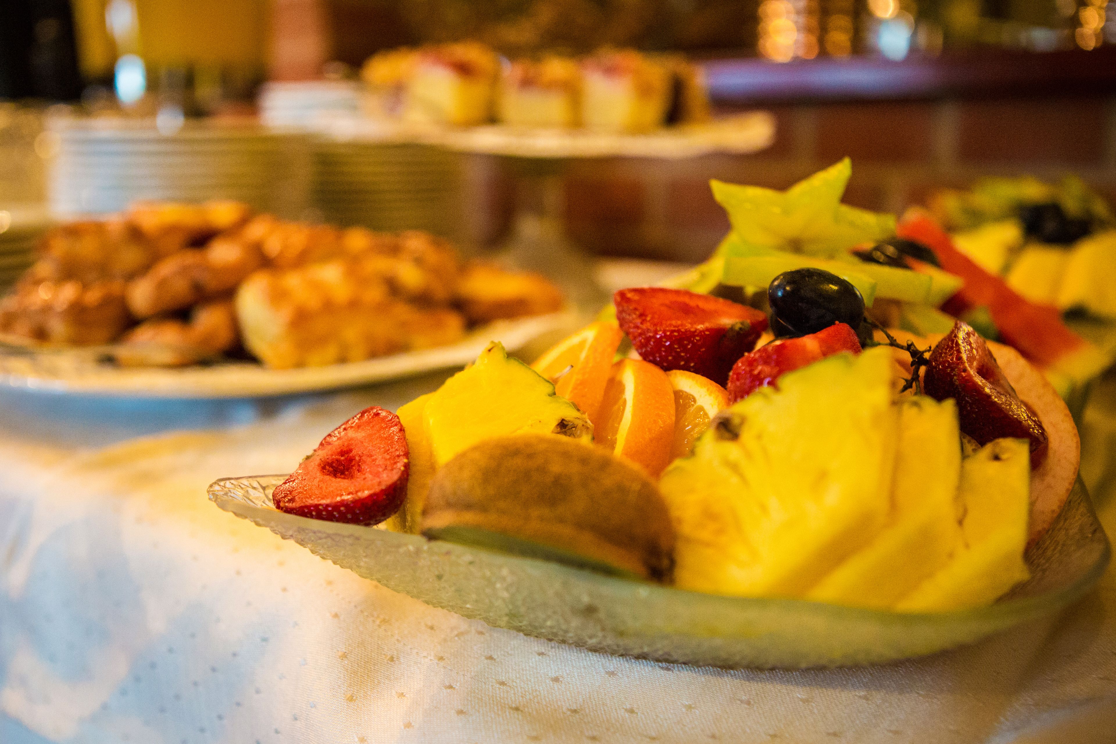 A buffet with various dishes including fruit and pastries.