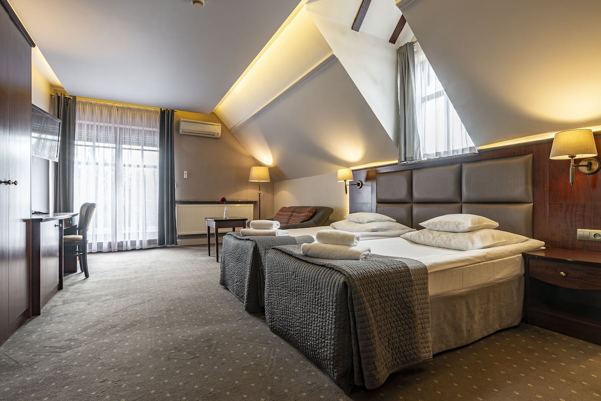 Een hotelkamer met een groot bed, twee nachtkastjes, een bureau en een stoel.