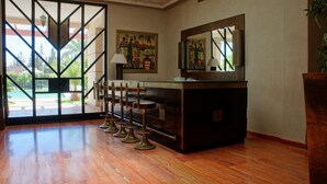 Eine Bar mit Barhocker und Theke, ein großer Spiegel und Kunstwerke an den Wänden.