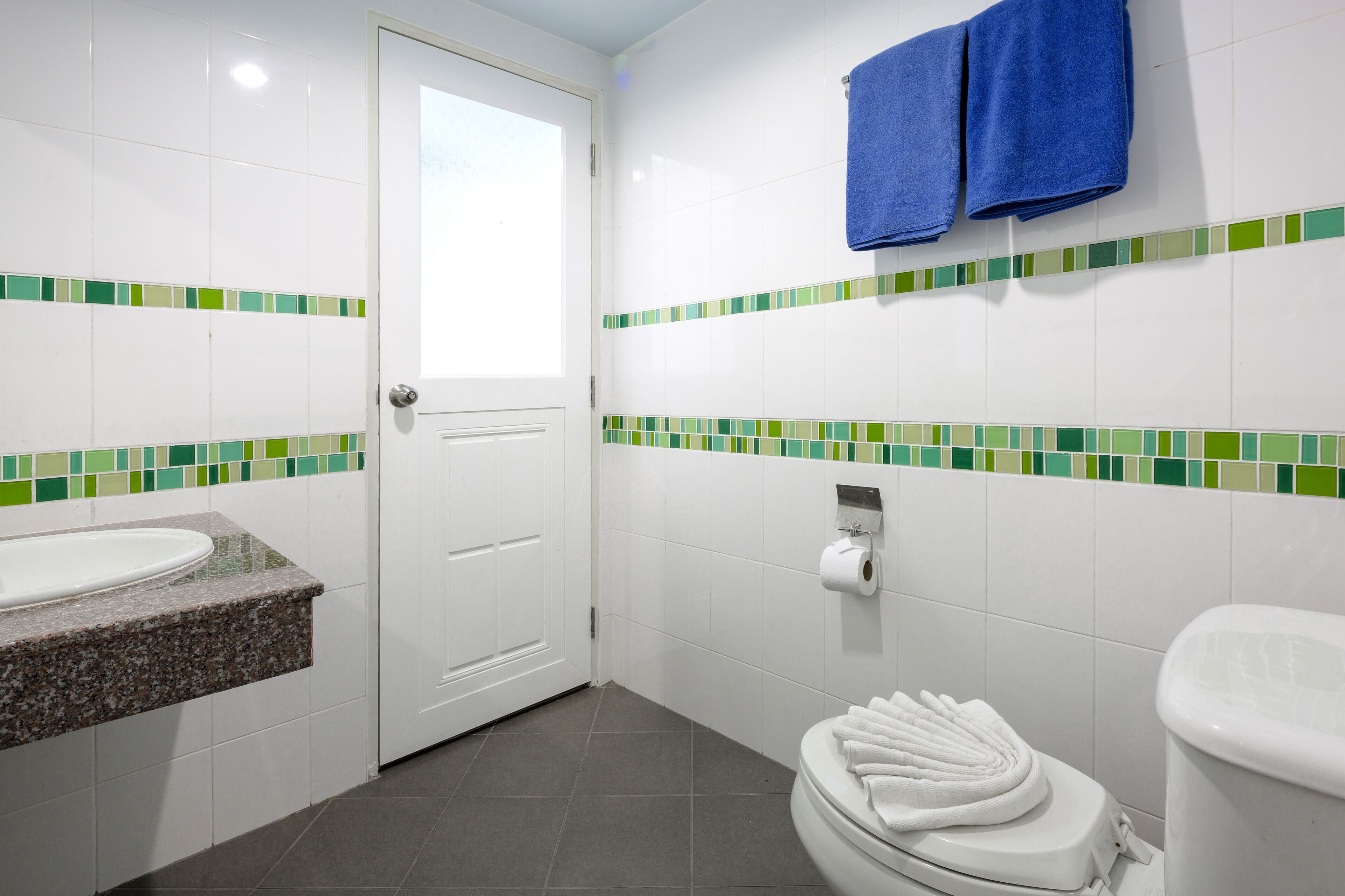 A bathroom with a white sink, toilet, and a towel rack with two towels.