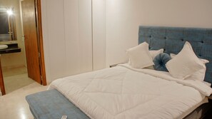 Ein Schlafzimmer mit einem Bett, Kissen, einem Nachttisch und einem Holzschrank.