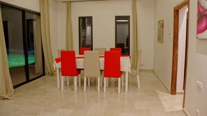 A dining area with a table set for six, surrounded by chairs with red cushions. - Plage Rouge Luxury Villas (Marrakech)