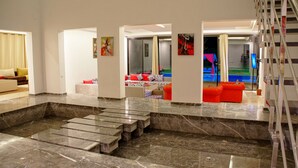 A spacious living area with a marble floor, a low seating area, and a staircase leading to an upper level. - Plage Rouge Luxury Villas (Marrakech)