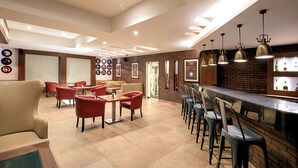 A modern restaurant with a bar area, red and black chairs, and a brick wall. - Lemon Tree Hotel Alwar (Alwar)