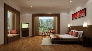 A hotel room with a bed, bedside tables, a TV, a window with a view of trees, and a painting on the wall. - Lemon Tree Hotel Alwar (Alwar)