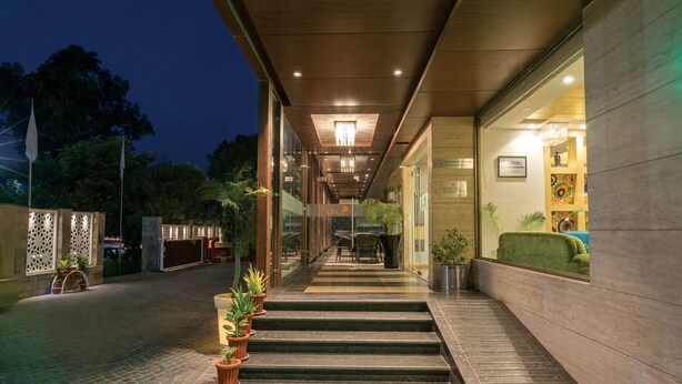A modern hotel entrance with a staircase leading to the lobby, potted plants, and a well-lit interior. - Lemon Tree Hotel Alwar (Alwar)