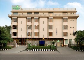 Un hotel de varios pisos con fachada plana, grandes ventanas y un letrero que indica que es el Limon Tree Hotel.
