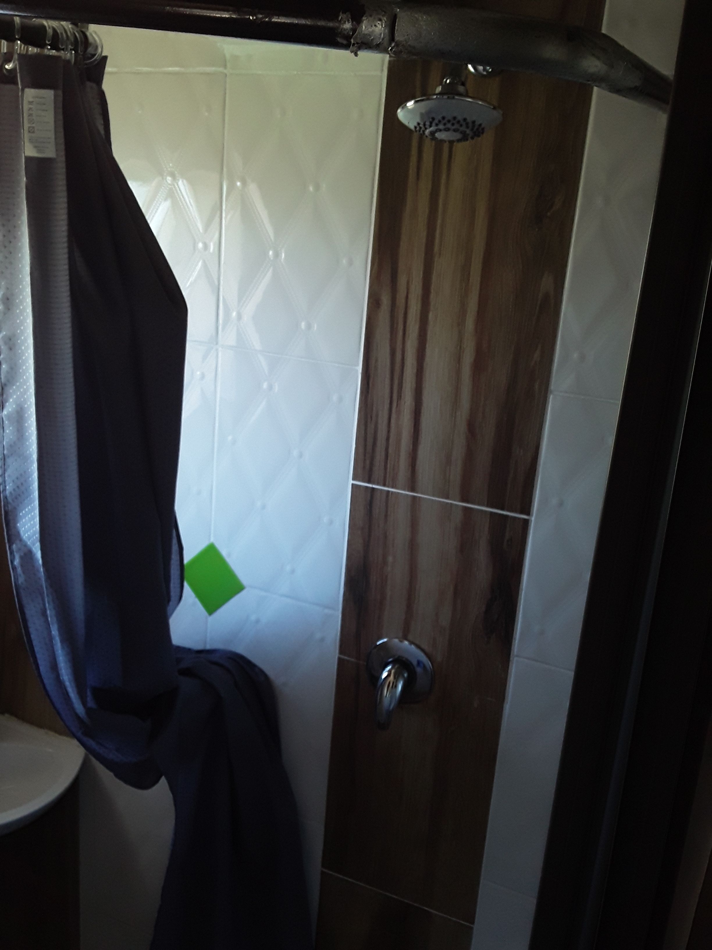 A shower area with a wooden door, a showerhead, and a towel hanging on a rack.