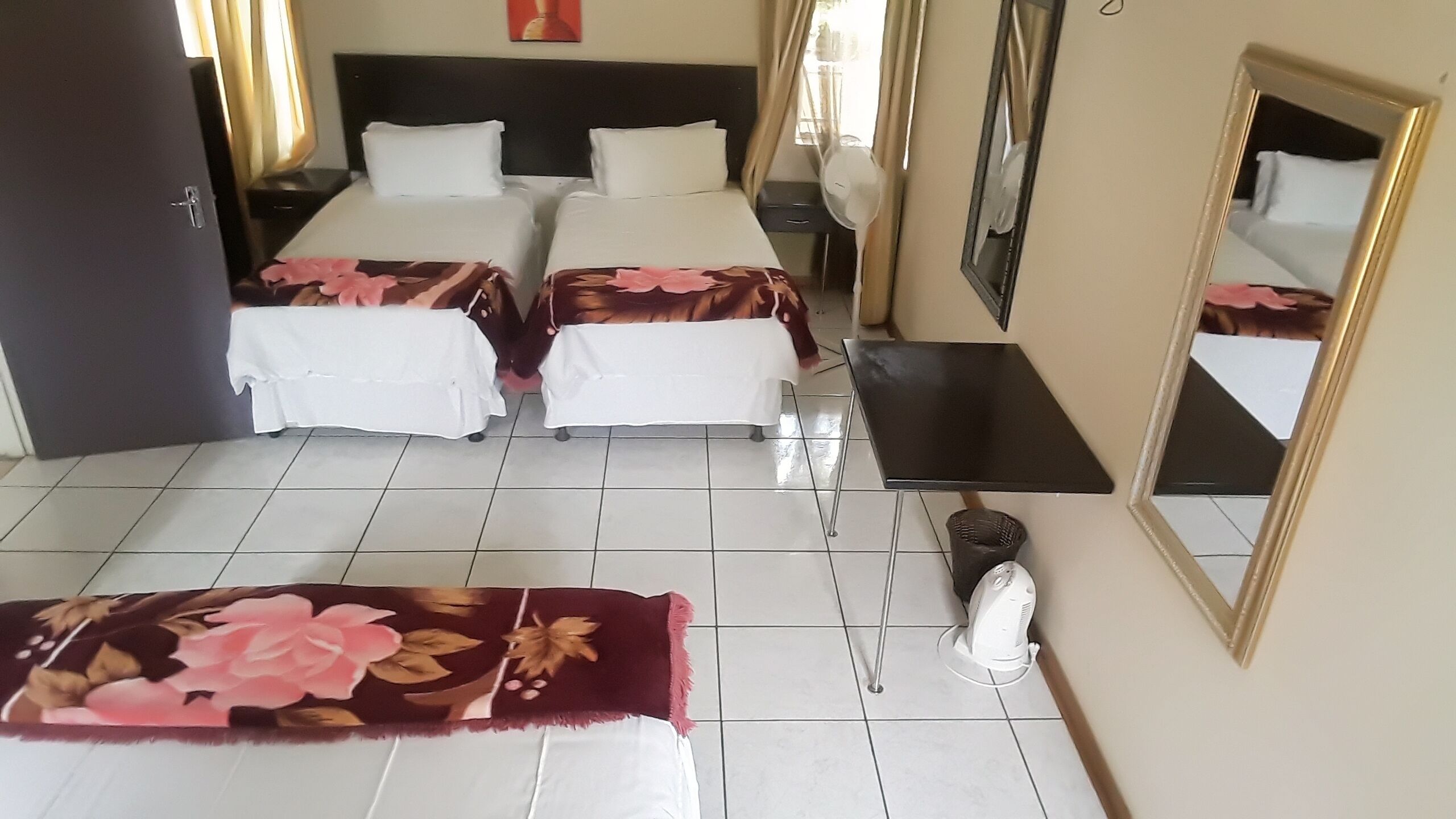 Habitación de hotel con dos camas, un escritorio, una silla, un espejo y una ventana.