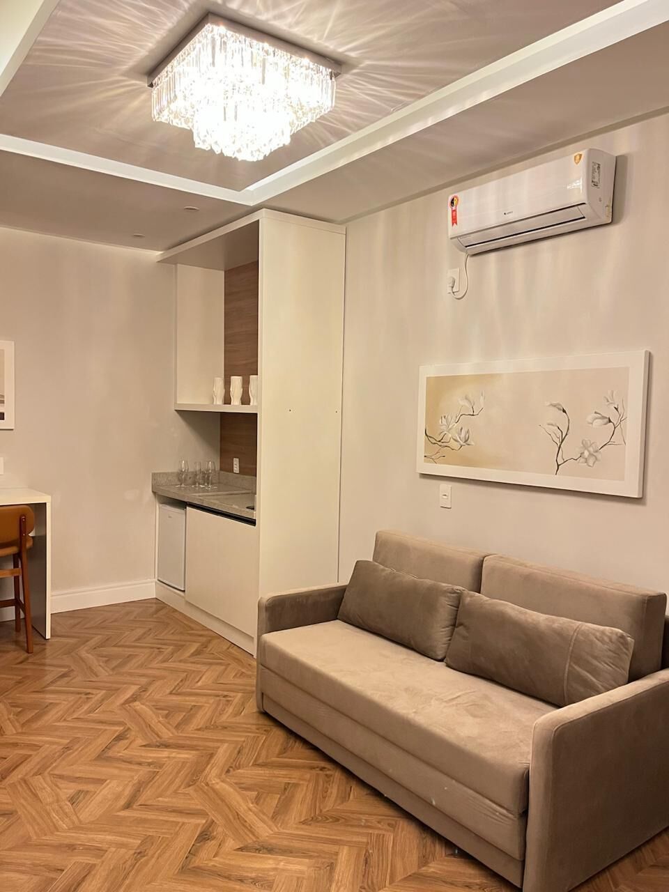 A modern living room with a sofa, a dining table, and a kitchen area.