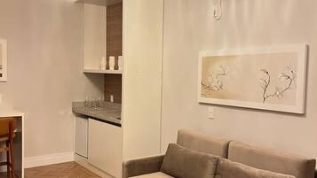 A modern living room with a sofa, a dining table, and a kitchen area.