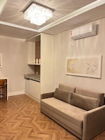Uma sala de estar moderna com um sofá, uma mesa de jantar e uma cozinha.