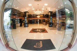 A hotel lobby with a chandelier, a reception desk, and a large glass door. - Hotel Jacques Georges Tower (Pelotas)