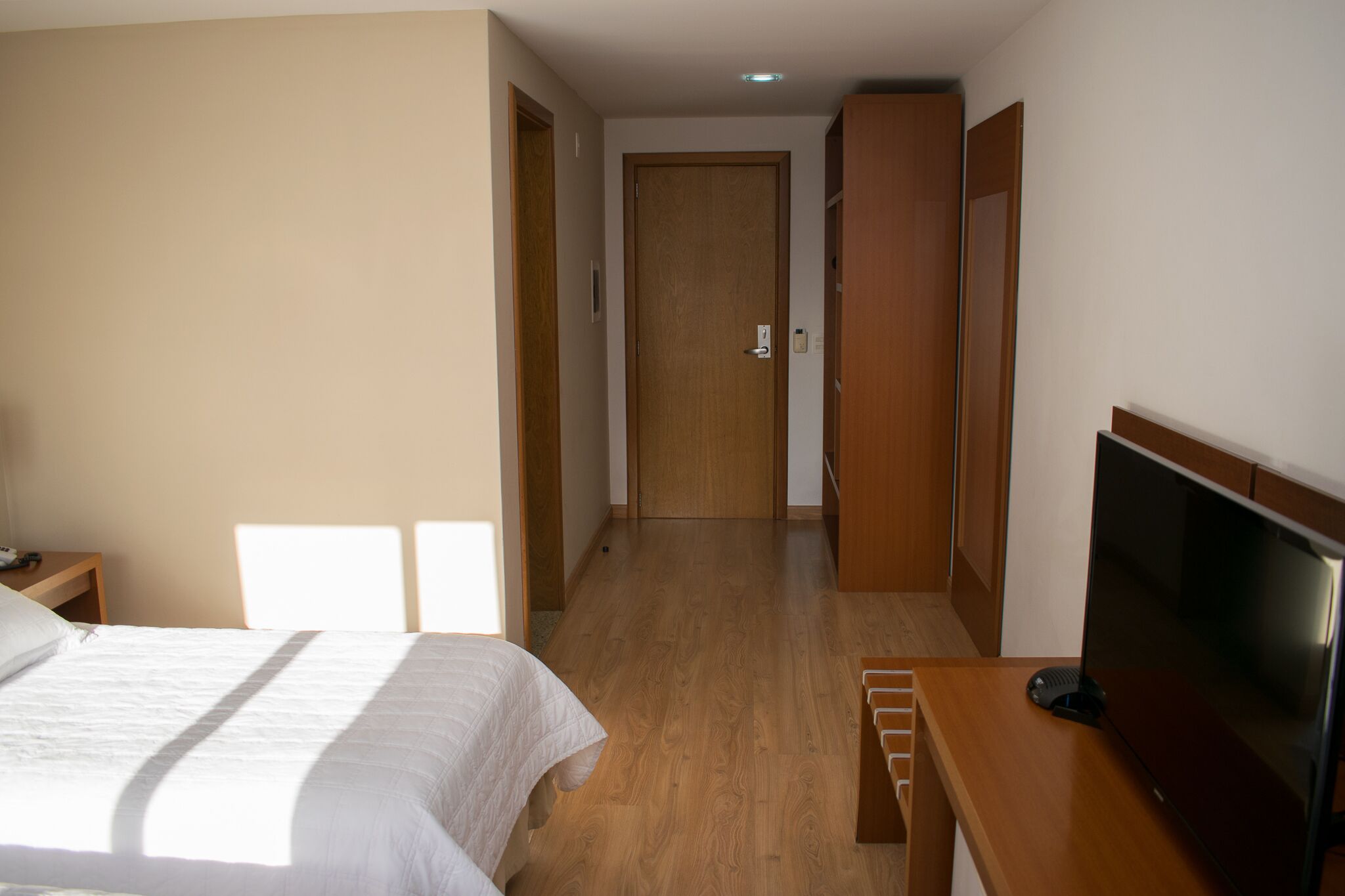 Habitación de hotel con cama, televisión, escritorio y armario de madera.
