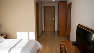 Habitación de hotel con cama, televisión, escritorio y armario de madera.