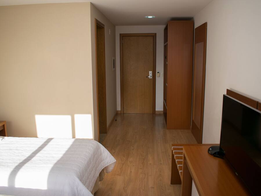 Habitación de hotel con cama, televisión, escritorio y armario de madera.