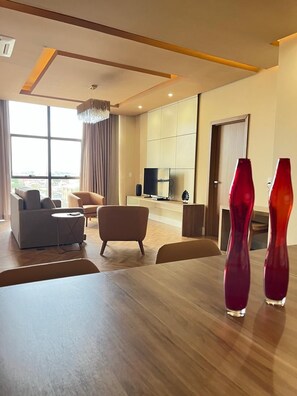 Una sala moderna con una mesa de comedor de madera, dos sofás y un televisor al fondo.