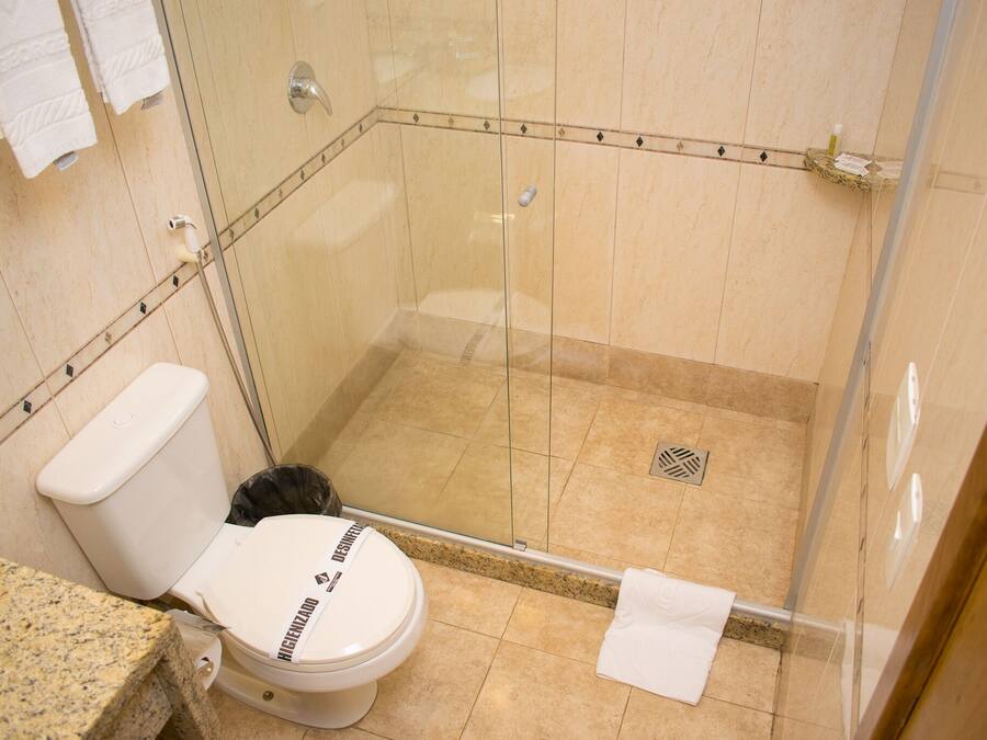 Een badkamer met een toilet, een douchegedeelte en een granieten aanrecht.