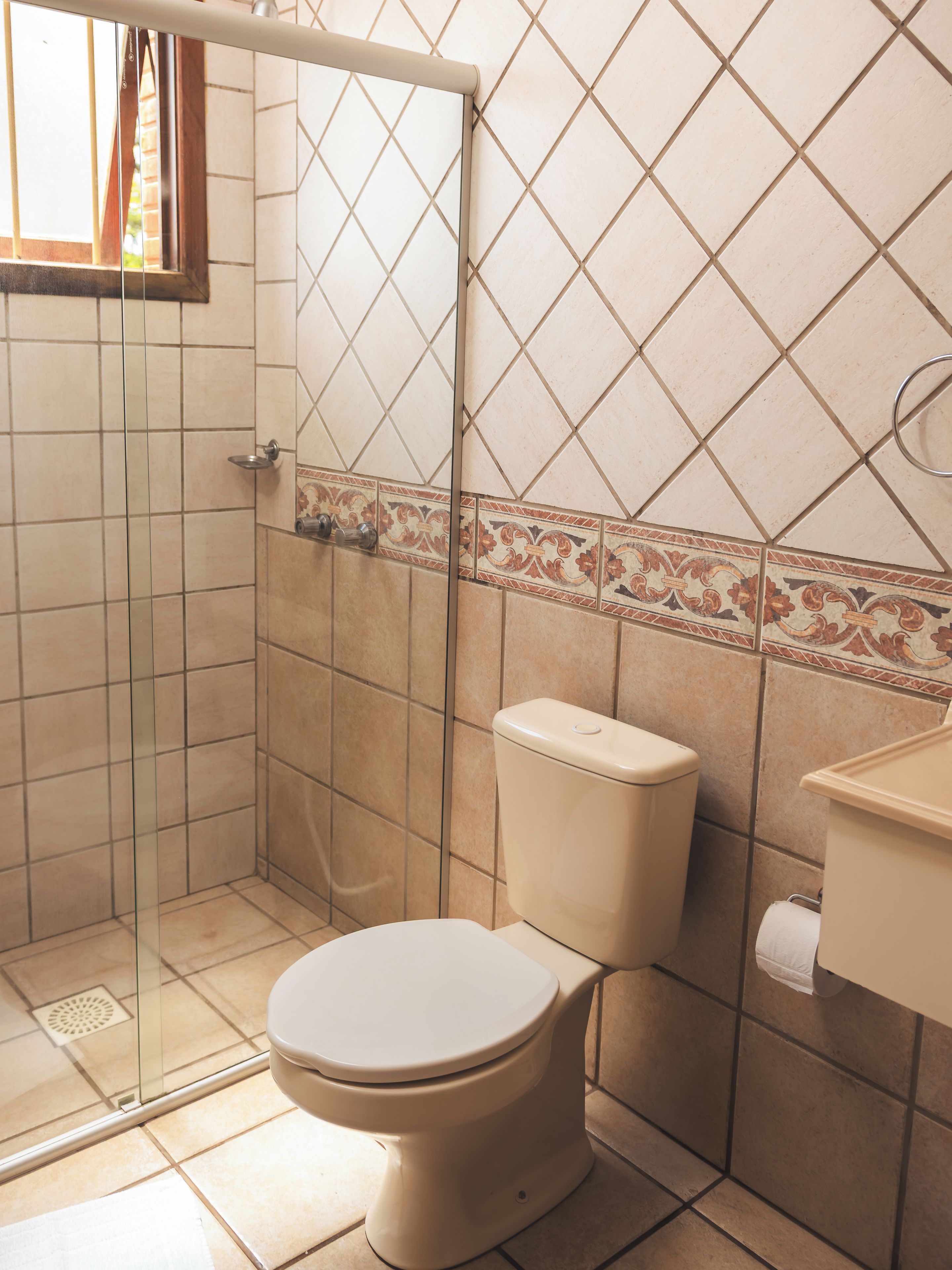 Un baño con inodoro, cabina de ducha y lavamanos.