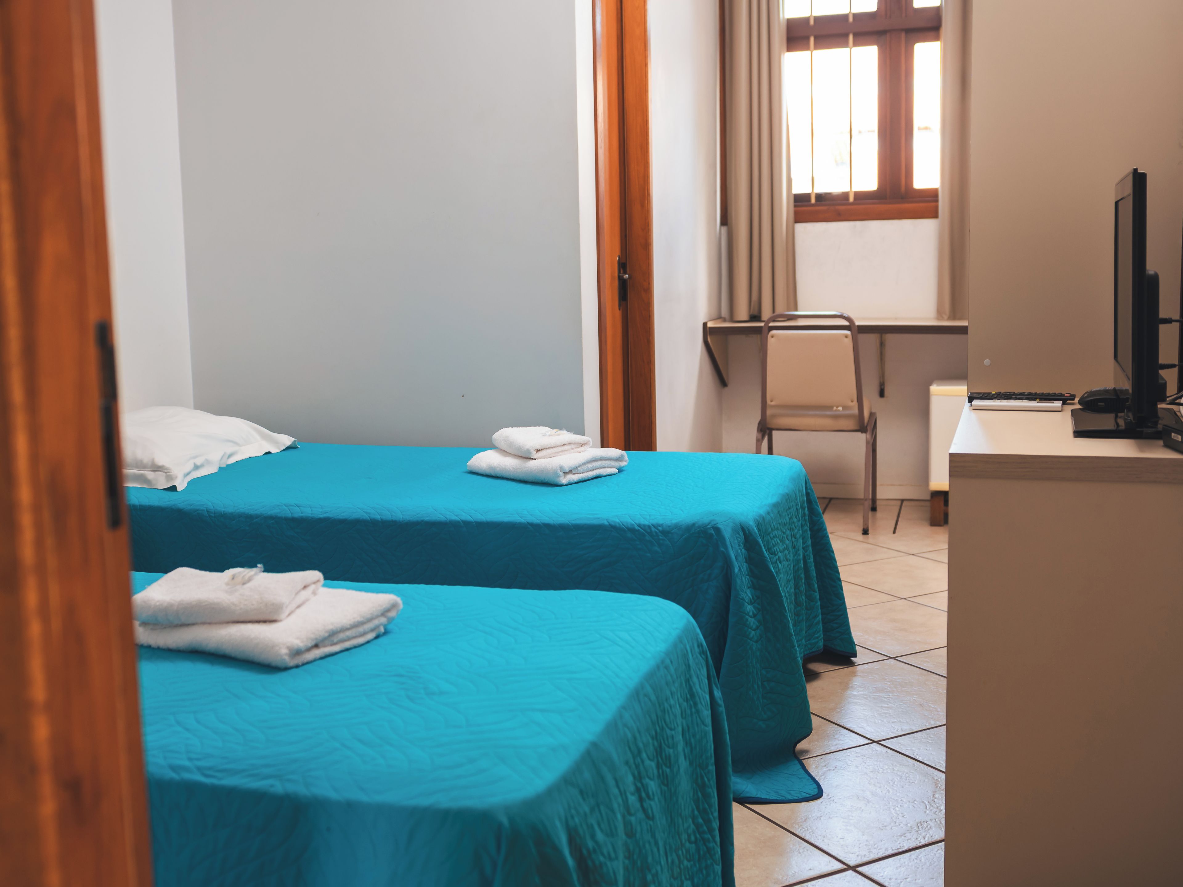 Una habitación de hotel con dos camas, un escritorio, una silla y un televisor.