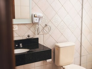 A bathroom with a black sink, a toilet, and a hairdryer mounted on the wall. - Sítio Hotel e Eventos (Sao Pedro do Sul)