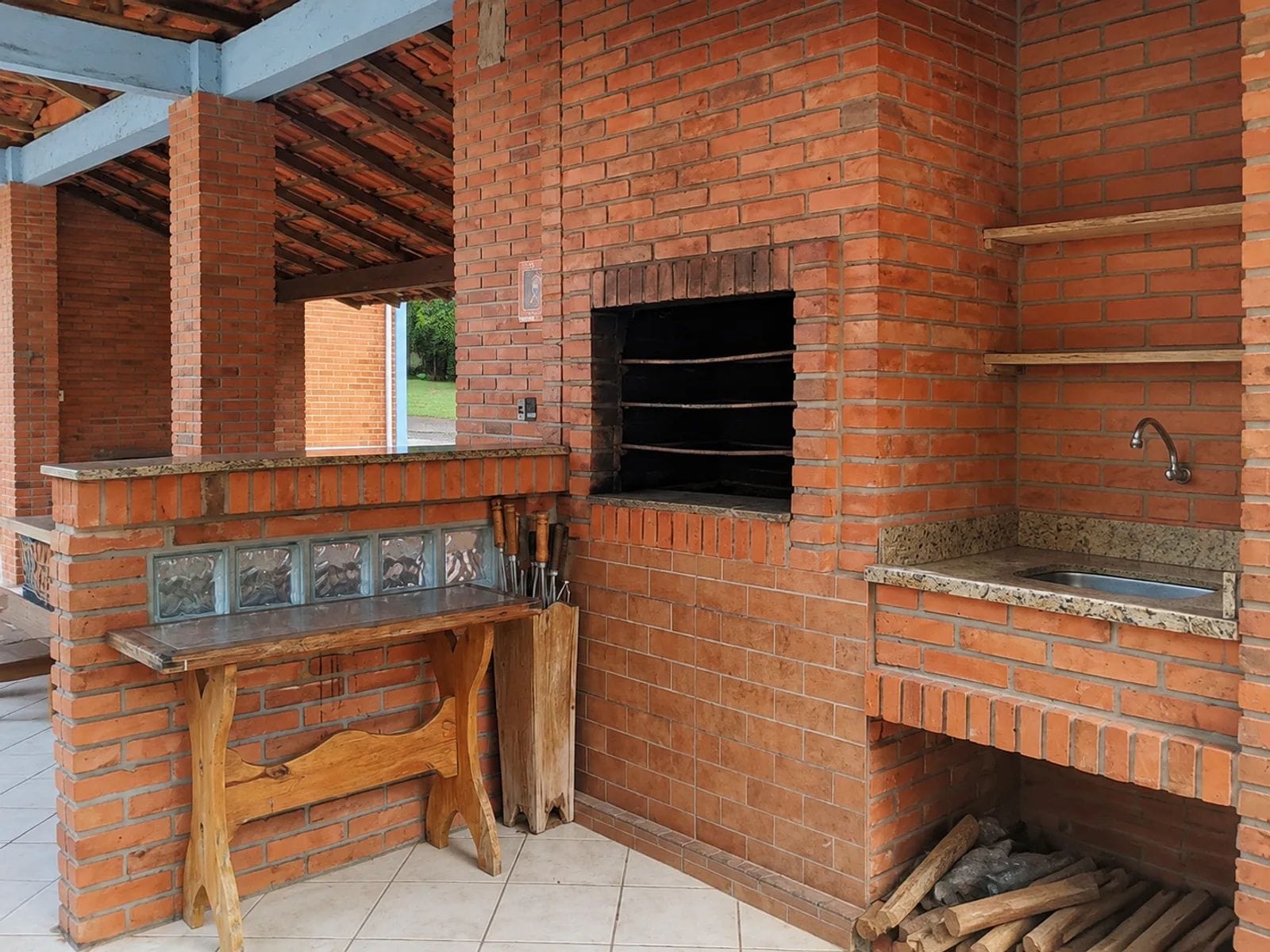 An outdoor brick barbecue area with a sink and a window.