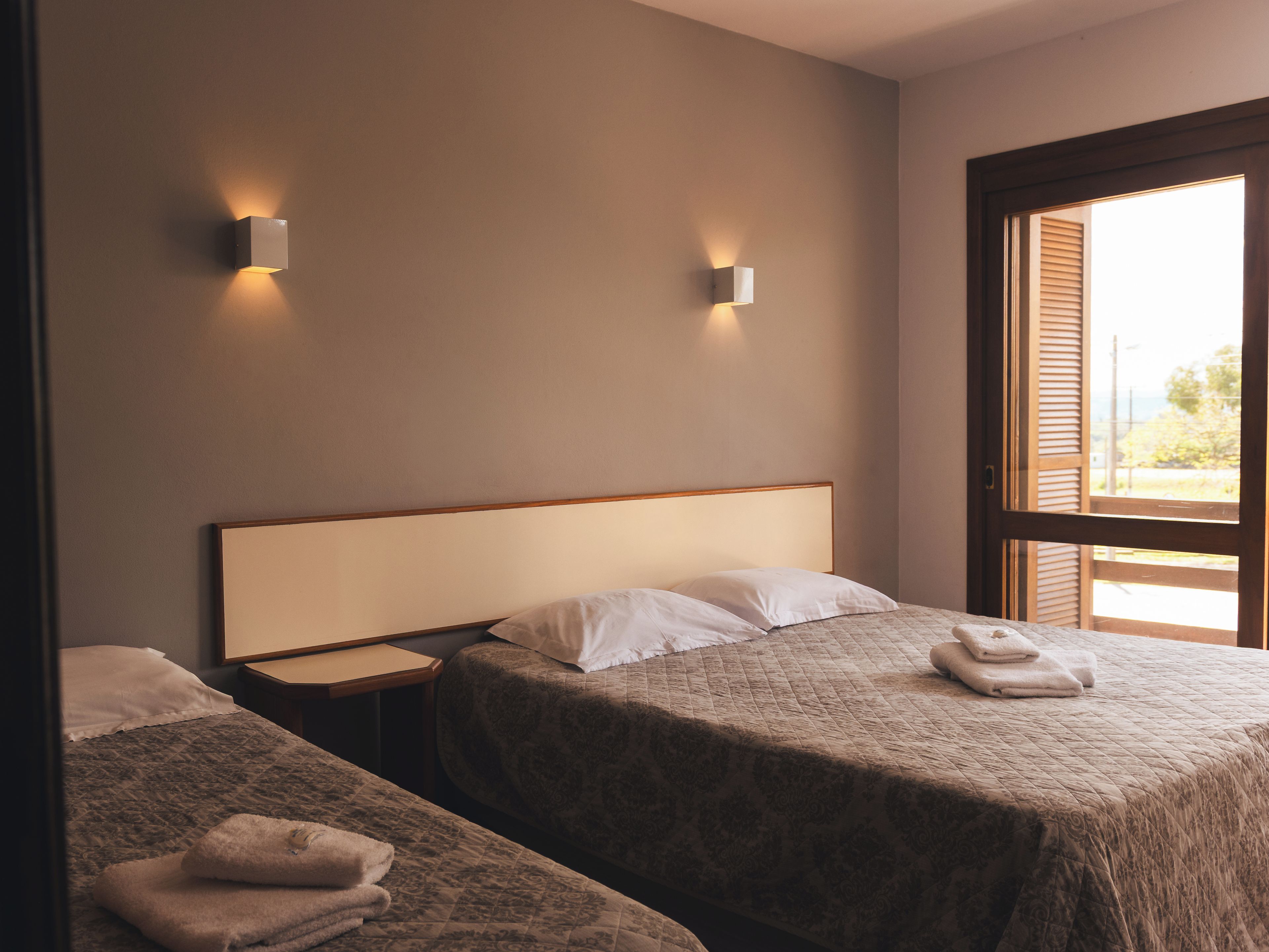 Ein Hotelzimmer mit zwei Betten, einem Nachttisch und einem Fenster mit Jalousien.