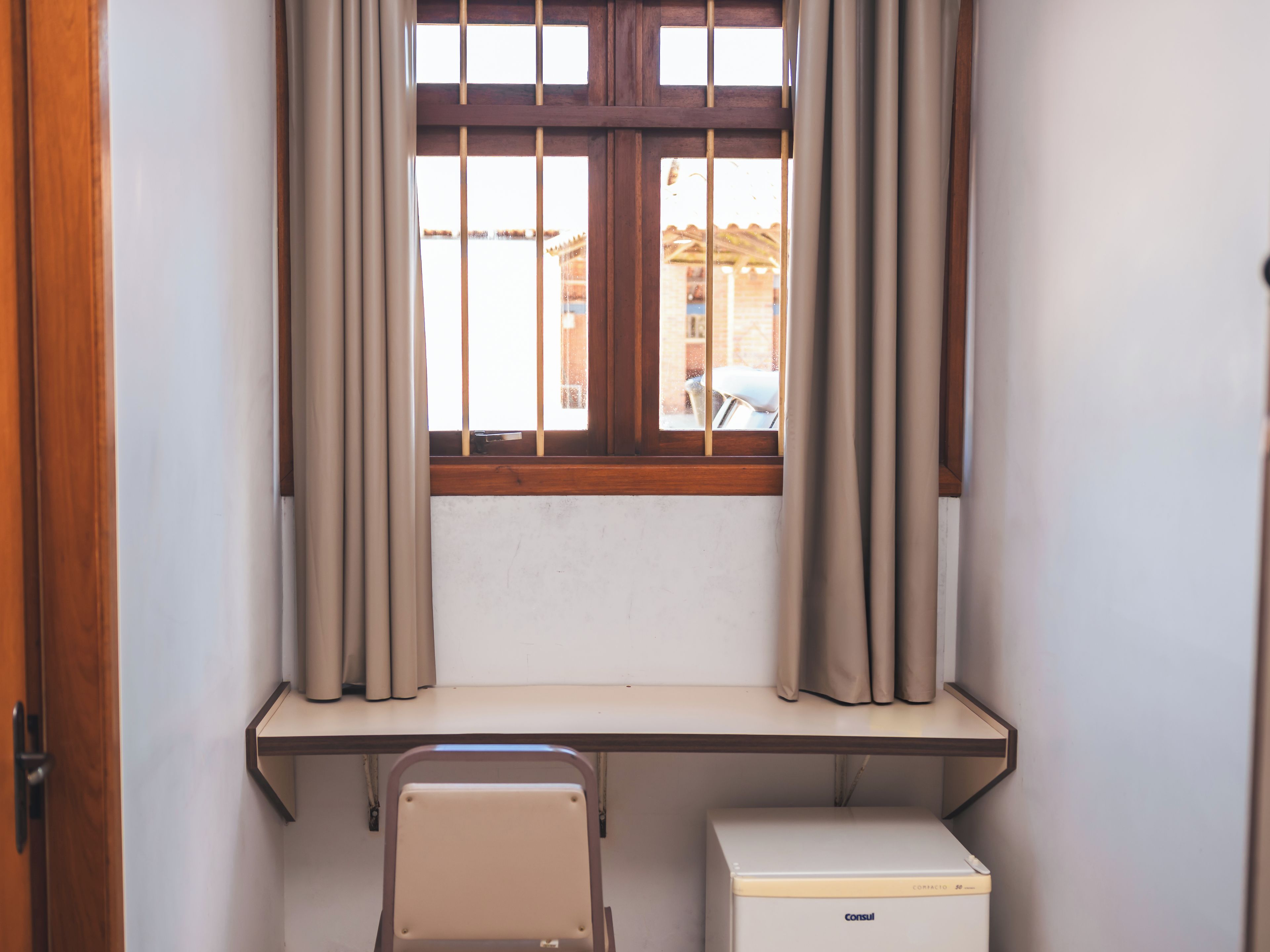 A room with a window, a desk, a chair, and a radiator.