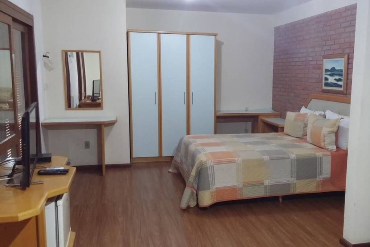 A bedroom with a bed, a desk, a wardrobe, and a mirror.