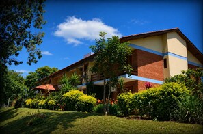 A two-story building with a flat roof, surrounded by lush greenery and a clear blue sky. - Sítio Hotel e Eventos (Sao Pedro do Sul)