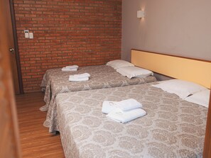 A hotel room with two beds, each with a patterned bedspread and pillows, and a brick wall. - Sítio Hotel e Eventos (Sao Pedro do Sul)