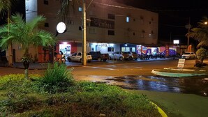 A hotel with a signboard, a parking area, and a street with parked cars. - Hotel Guima (Santa Vitoria)