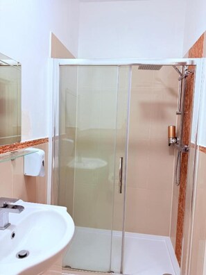 A bathroom with a glass shower enclosure, a white sink, and a towel dispenser. - RBS Hotel, Rochester (Rochester)