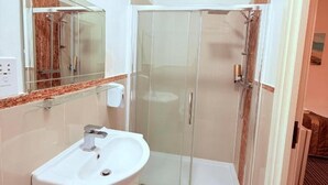 Une salle de bain moderne avec une douche à parois de verre, un lavabo blanc et un miroir au-dessus.